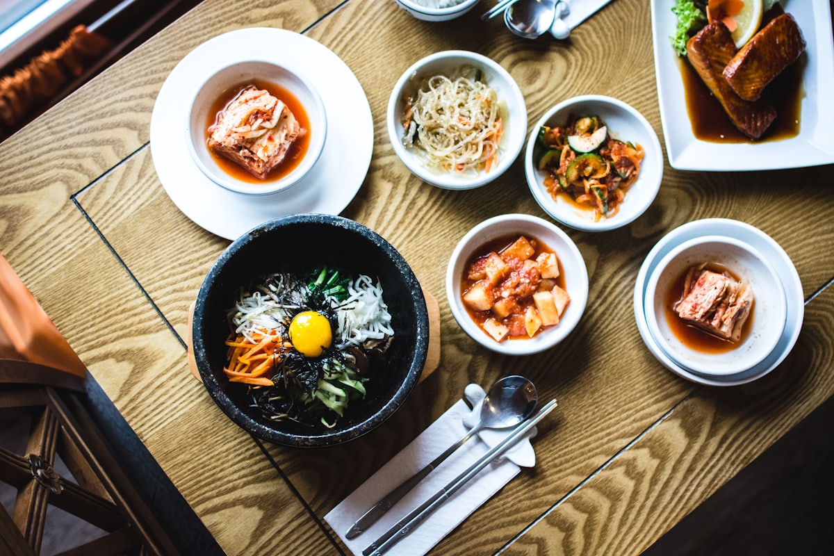 A Korean table set with bibimbap in a stone bowl and an array of shared banchan side dishes.